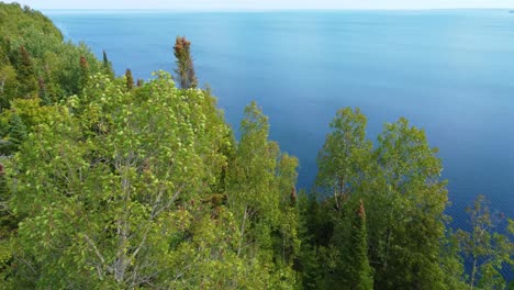 Aerial-view-of-blue-lake-stone-shore-and-and-green-forest