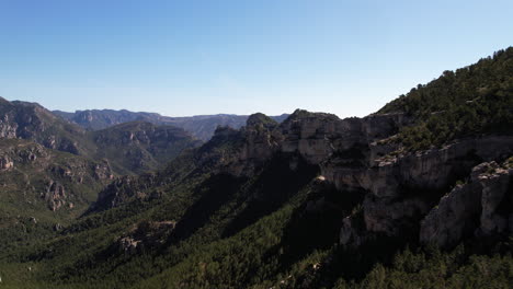 Tourists-Hikers-On-Summit-of-Rocky-Cliff-at-Portell-de-l'Infern-in-Spain,-Mountainous-Natural-Park-in-Tinença-de-Benifassà,-Castellón-Region,-Aerial-View