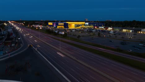 Hyperlapse-Drohnenvideo-Des-Verkehrs,-Der-Nachts-An-Einem-Großen-IKEA-Laden-In-Ottawa,-Ontario,-Kanada,-Vorbeifährt