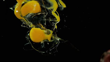 Raw-eggs-splash-into-water-against-black-background