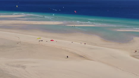 Menschen-Beim-Kitesurfen-Am-Weiten-Strand-Und-Im-Blauen-Wasser-Von-Fuerteventura