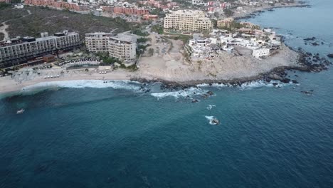 Aerial-view-over-the-beautiful-coast-of-los-cabos-with-a-view-of-luxurious-hotels-like-the-hyatt-hotel,-the-monument-beach-and-blue-sea-during-an-exciting-mexico-trip