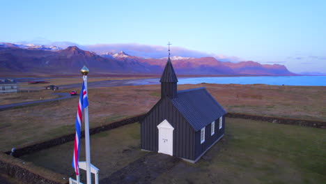Búðakirkja-black-church-and-Iceland´s-flag-under-sunset-sky