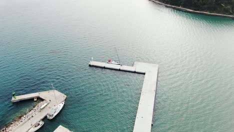 A-drone-shot-of-a-lone-sailing-boat-being-docked-on-a-stone-pier