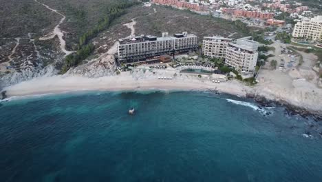 Aerial-shot-from-a-beautiful-hotel-overlooking-the-multi-story-building,-swimming-pools-and-vacationers-at-the-cape-thompson-hotel-in-los-cabos-on-monument-beach-with-blue-sea-during-a-mexico-vacation
