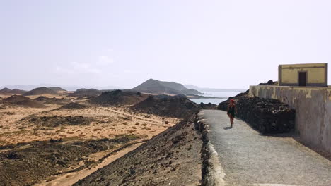 A-woman-walking-on-a-pathway-with-a-scenic-view-of-Los-Lobos-Island