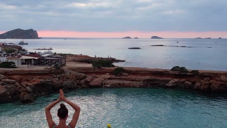 Majestic-aerial-top-view-flight-Yoga-Girl-position-tree-sunset-cliff-beach-island-ibiza-Spain-overflight-flyover-drone