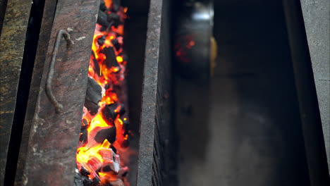 Slow-motion-of-red-hot-burning-charcoal-with-flames-in-a-rusted-restaurant-grill