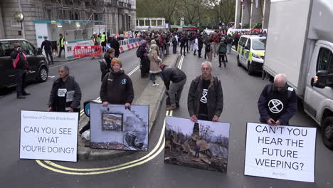 Extinction-Rebellion-activists-block-a-road-with-photographic-placards-depicting-climate-change-disasters-at-the-Intercontinental-Hotel-in-Mayfair-where-the-Energy-Intelligence-Forum-is-taking-place