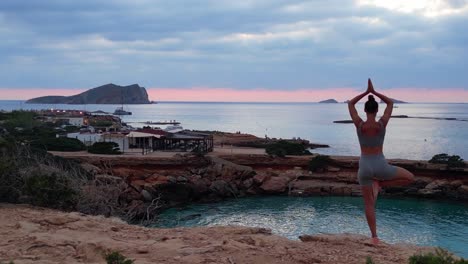 Young girl practising yoga on a beach during sunrise - Crystalika