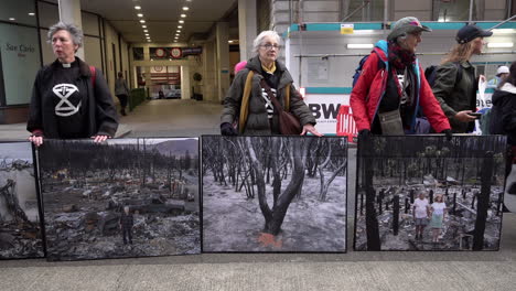 Three-Extinction-Rebellion-activists-stand-with-photographic-placards-depicting-climate-change-disasters-outside-the-Intercontinental-Hotel-where-the-Energy-Intelligence-Forum-is-taking-place