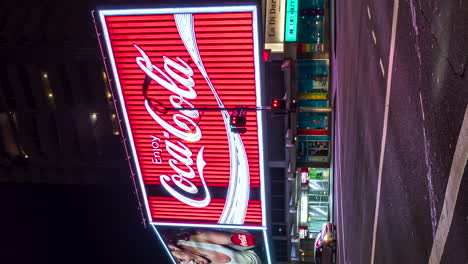 Iconic-Coca-Cola-neon-sign-in-Sydney-at-night-with-street-traffic---vertical-time-lapse