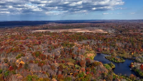 An-aerial-view-high-up-over-colorful-trees-and-a-lake-on-a-sunny-day-in-New-Jersey-on-s-sunny-day