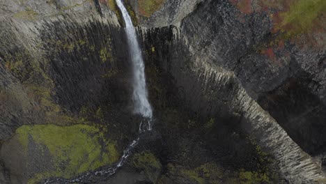 Aerial-top-down-show-of-crashing-waterfall-into-ravine-of-Iceland-during-daytime---Tilt-up-movement