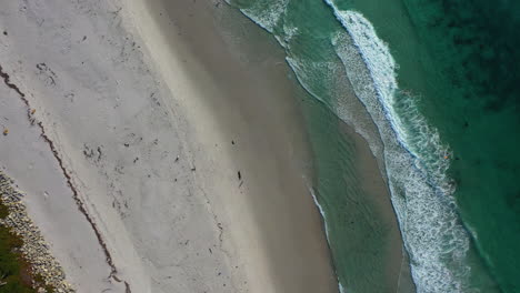 Aerial-view-rotating-above-beach-and-waves,-in-Carmel-by-the-sea,-Monterey,-USA