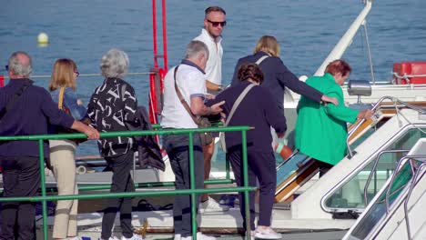 Elderly-passengers-are-helped-boarding-a-sightseeing-boat-at-the-docking-point-in-the-port-of-Stresa,-Lake-Maggiore,-Piedmont,-Italy-in-order-to-go-on-a-boat-trip