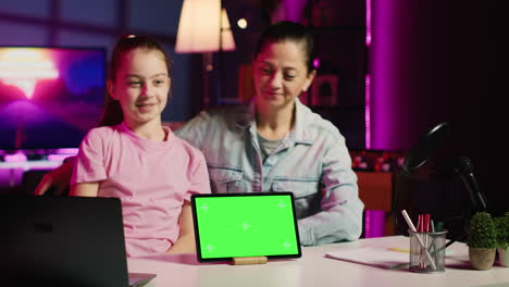 Happy-child-and-her-loving-mom-recording-green-screen-laptop-review-on-online-platforms
