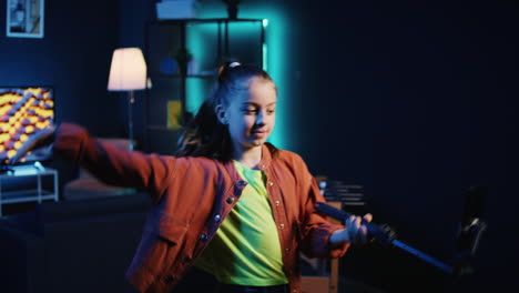 Smartphone-on-selfie-stick-used-by-talented-gen-z-kid-in-dark-room-doing-viral-dance-choreography