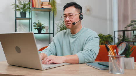 Asian-man-freelance-worker-call-center-or-support-service-operator-helpline-having-talk-with-client