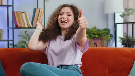 Happy-young-woman-looking-approvingly-at-camera-showing-thumbs-up,-like-positive-sign,-good-news