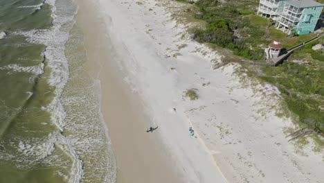 Aerial-of-Beach-at-Cape-San-Blas,-Florida-following-walking-couple