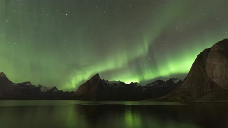 Time-Lapse-of-strong-aurora-borealis-dancing-over-the-mountains-in-Hamnøy,-Lofoten