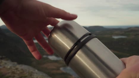 Person-Opening-A-Coffee-Thermo-Flask-During-Mountain-Hike