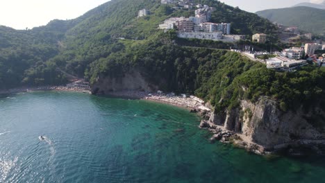Aerial-view-of-hidden-sandy-Mogren-beach-under-the-cliff-in-Budva,-Montenegro