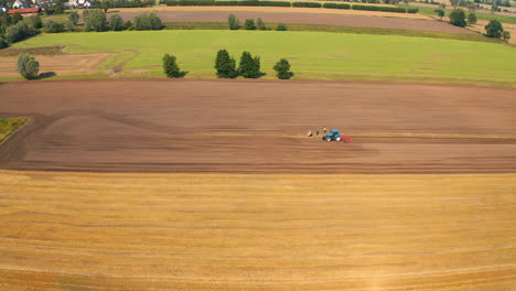 Aerial-view-of-drone-flying-above-farmland-with-tractor-on-the-field