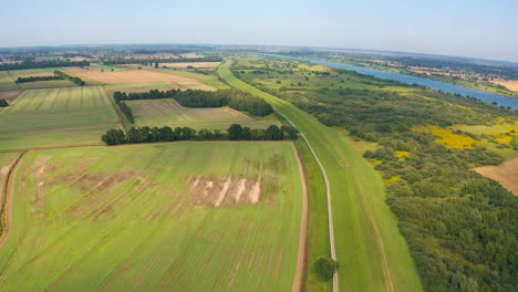 Aerial-top-view-of-drone-flying-above-farmland-river-in-the-background