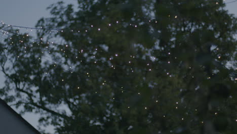 Handheld-shot-of-a-light-string-placed-outside-a-house,-making-star-patterns-at-sunset