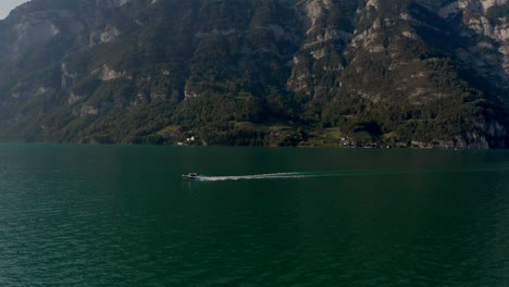 Flyby-and-pursue-shot-of-a-small-motorboat-across-a-mountain-lake-in-Switzerland-at-summer