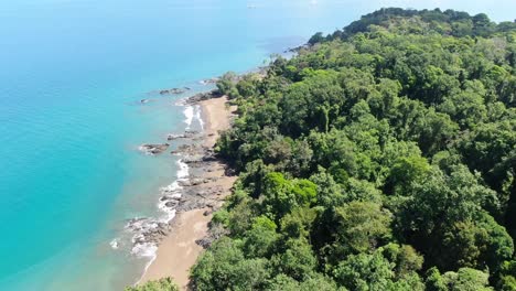 Costa-Rica-beach-drone-view-showing-sea,-shore-and-palm-tree-forest-in-Corcovado-National-Park-on-Osa-Peninsula-on-a-sunny-day-in-the-pacific-ocean