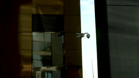 Security-camera-on-a-building-with-golden-reflective-windows-and-a-shadow