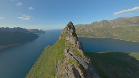 Aerial-flight-on-summit-of-mountains-on-Senja-Island-during-sunny-day-in-Norway---Blue-Fjord-landscape-in-background