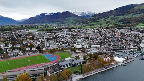 Lachen-city-with-sports-centre-and-yacht-harbour-port,-establishment-drone-overview,-Swiss-village-in-mountain-landscape