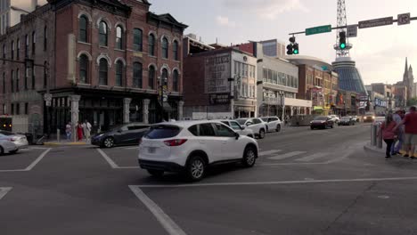 Cars-driving-along-Broadway-Street-in-Nashville,-Tennessee-with-pedestrians-in-slow-motion