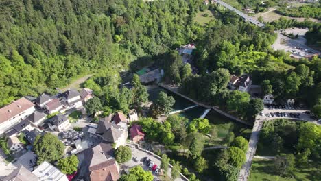 Aerial-view-circling-Jajce-small-Bosnian-city-rooftops,-Herzegovina-beautiful-countryside-woodland-forest-trees