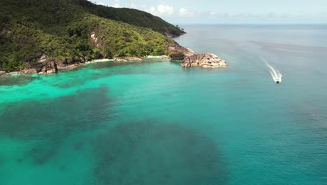 Drone-of-Anse-major-beach,-passing-speed-boat-from-rice-beach,-granite-stones,-turquoise-water,-Mahe-Seychelles-30-fps