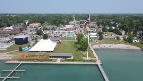 Iconic-American-town-with-waving-flag-near-lake,-aerial-drone-view