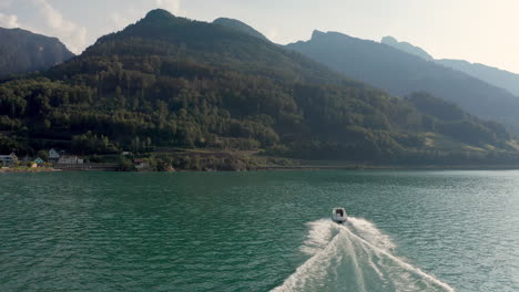 Medium-slow-motion-shot-pursuing-a-small-motorboat-across-a-mountain-lake-in-Switzerland-at-summer
