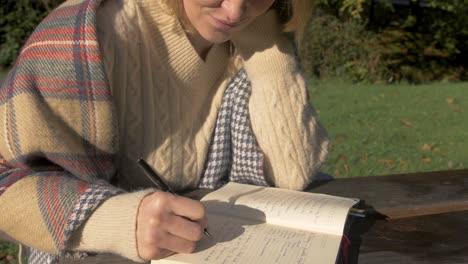 Female-student-studying-writing-outdoors-wearing-sweater