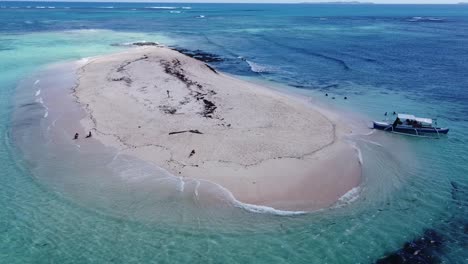 Tourists-and-tour-boat-on-tiny-sandbank-of-naked-island-in-Siargao,-Aerial