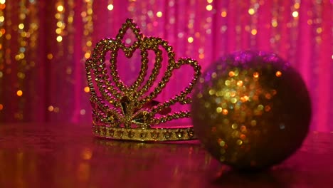 A-gold-sparkling-tiara-sits-in-front-of-a-pink-background