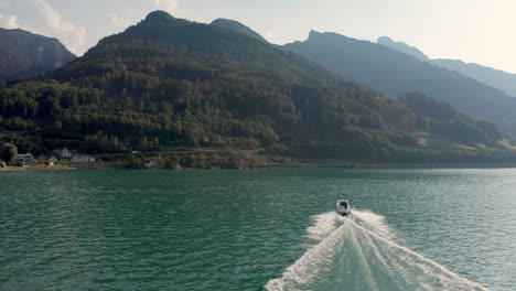 Super-slow-motion-shot-pursuing-a-small-motorboat-across-a-mountain-lake-in-Switzerland-at-summer