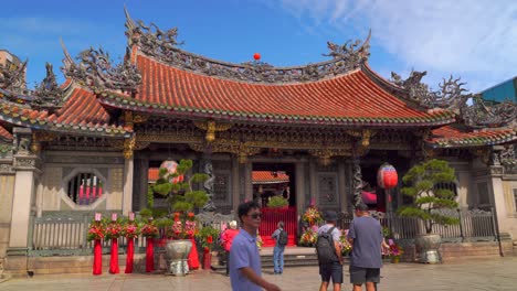 Frontal-view-of-Longshan-Temple-in-Taipei-with-tourists-walking-through-frame