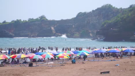 Colourful-sun-umbrellas-and-people-on-the-beach---Baron-Beach,-Indonesia