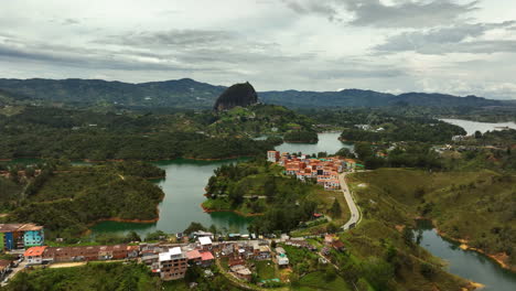 Aerial-view-over-a-town,-toward-the-monolith-rock,-in-Guatape,-Antioquia,-Colombia