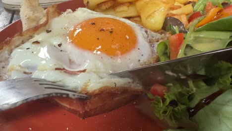 Eating-a-slice-of-meatloaf-and-fried-egg-with-salad-close-up-Messy-eating
