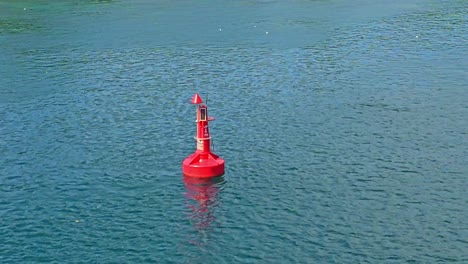 A-red-navigation-buoy-swaying-gently-in-a-calm-rippling-ocean